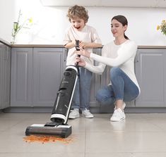 two women are cleaning the floor with a vacuum