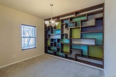 an empty room with a large book shelf in the corner and a chandelier hanging from the ceiling