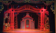 the stage is lit up with red lights and elaborate arches, which are adorned with statues