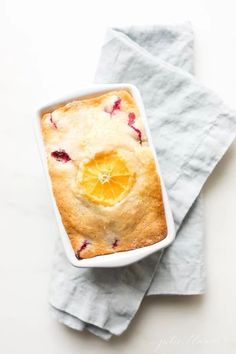 an orange and raspberry cobbler in a white dish on top of napkins