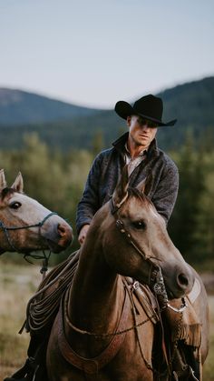 a man riding on the back of a brown horse next to another horse in a field