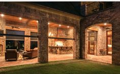 an outside view of a house with stone pillars and brick walls at night, lit up by outdoor lighting