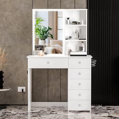 a white desk with drawers and a mirror on it's side next to a plant