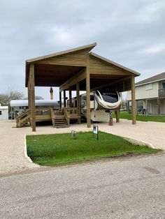 an airplane is parked under a covered area on the grass in front of a building