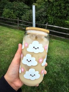 a person holding up a cup with clouds on it