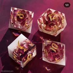 three glass boxes with gold numbers and flowers in them on a purple tableclothed surface