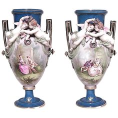 two blue vases with cherubs on them sitting next to each other in front of a white background