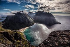 two mountains with water and clouds in the sky above them on top of a mountain