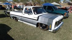 an old pickup truck is parked in the grass at a car show with other cars