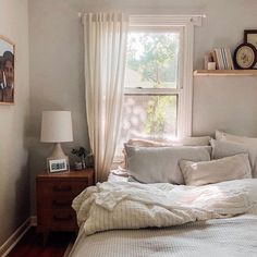 an instagramted photo of a bed with pillows and blankets in front of a window