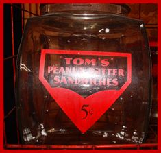 a glass jar with a red and black label on it that says tom's peanutster sandwiches