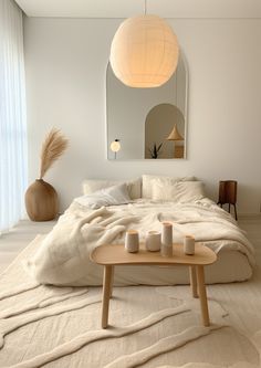 a white bed sitting in a bedroom next to a table with candles on top of it