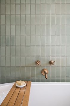 a bathroom with a wooden bench in front of the bathtub and tile wall behind it