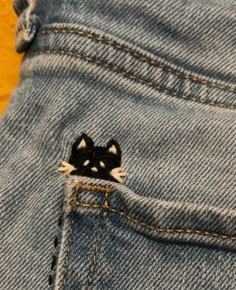 a small black and white cat sticking out of the back pocket of a pair of jeans