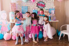 a group of girls standing next to each other in front of a cake table with balloons and decorations