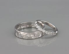 two white gold wedding rings with diamonds on top, one in the shape of a wave