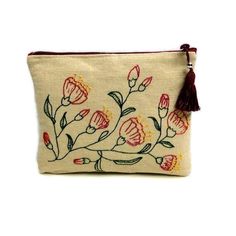 a small embroidered pouch with flowers and tassels on the front, sitting on a white surface