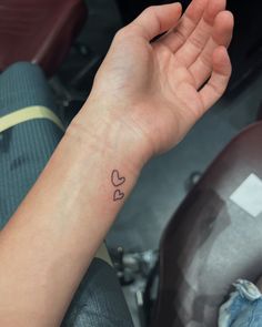 a person's arm with a small heart tattoo on the left wrist and right hand