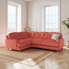 an orange sectional sofa in a living room with hardwood flooring and large windows on the wall