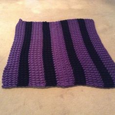 a purple and black crocheted rug on the floor