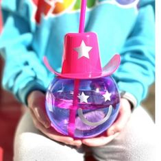 a person wearing a pink hat holding a purple ball with stars and crescent on it