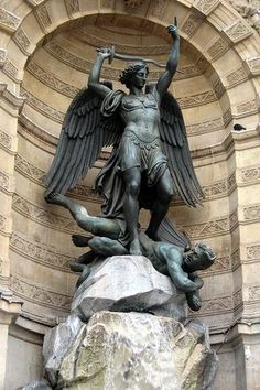 an angel statue on top of a rock in front of a stone arch with carvings