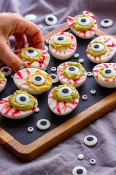 an assortment of decorated cookies on a wooden tray with eyes and googly eyes painted on them