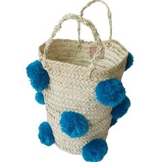 a basket with blue pom - poms hanging from the handle and inside it