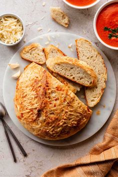 a plate topped with bread next to bowls of soup