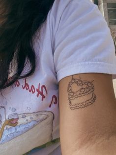 a woman's arm with a cake tattoo on the left side of her arm