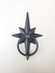 a black metal object on a white surface with a circular ring in the shape of a star