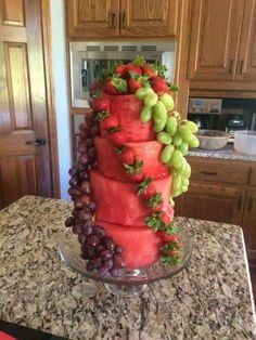 a cake made to look like it has grapes and strawberries on top, sitting on a kitchen counter