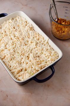 a casserole dish filled with rice next to a measuring cup on a counter