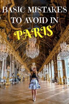 a woman standing in the middle of a hall with chandeliers