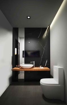 a white toilet sitting next to a bathroom sink under a mirror in a black and white room