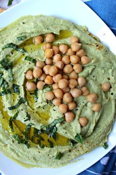 hummus with spinach and chickpeas in a white bowl on a blue towel