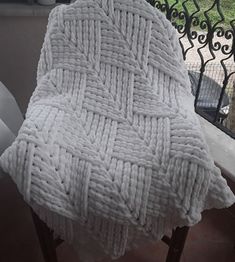 a white blanket sitting on top of a wooden chair