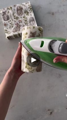 a person holding a green and white ironing board next to a box with flowers on it