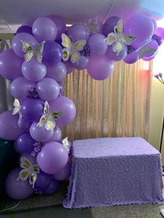 a bunch of balloons that are in the shape of butterflies on a table with a purple cloth