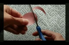 a person cutting paper with scissors on top of a piece of cloth that has been cut into smaller pieces