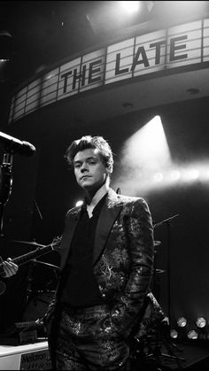 a man in a suit and tie standing next to a microphone on stage at the late show