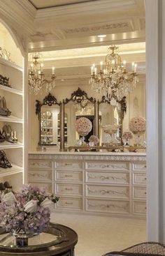 a room filled with lots of white furniture and chandelier hanging from the ceiling