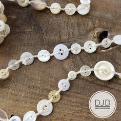 a white beaded necklace with buttons attached to it on top of a wooden table