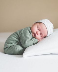 a newborn baby sleeping on top of a white pillow with a knitted headband