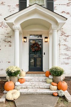 the front door is decorated with pumpkins and gourds