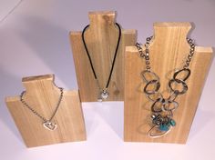 three pieces of jewelry are on display in wooden stands with chains and pendants hanging from them