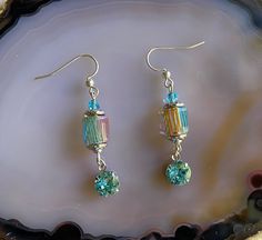 Item Number E-2576. Sterling Silver French Earwires. Length is 1 7/8 inches (48mm) from top of earwire. Turquoise crystal drop measures 8mm, with rhodium-plated setting. Cane glass bead measures 9mm tall by 9mm wide. These fun earrings feature crystal drops made from superior quality crystal.  The cane glass beads have delicate stripes in colors of turquoise, pale orange, and green.  A 4mm light turquoise crystal bead sits atop the cane glass bead, with complimentary silver accents.  These beaut Aquamarine Dangle Earrings With Ear Wire, Turquoise Aquamarine Dangle Earrings, Nickel-free Turquoise Crystal Earrings For Gift, Hypoallergenic Czech Glass Dangle Crystal Earrings, Turquoise Dangle Crystal Earrings For Jewelry Making, Silver Tassel Earrings, Black Earrings Dangle, Pale Orange, Turquoise Crystal