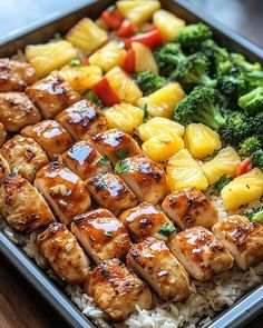 chicken, pineapples, broccoli and pineapple slices on rice in a pan