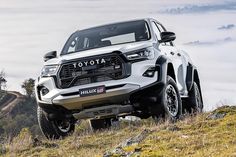 the front end of a white toyota hilux parked on top of a hill