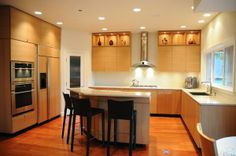 a kitchen with wooden floors and stainless steel appliances in it's center island area